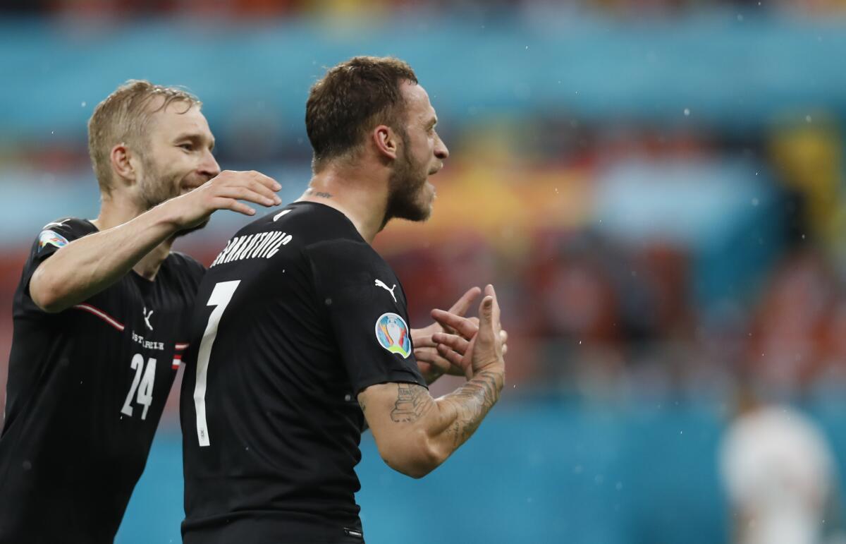Austria's Marko Arnautovic, right, celebrates after scoring his side's third goal during the Euro 2020 soccer championship group C match between Austria and Northern Macedonia at the National Arena stadium in Bucharest, Romania, Sunday, June 13, 2021. (Robert Ghement/Pool via AP)