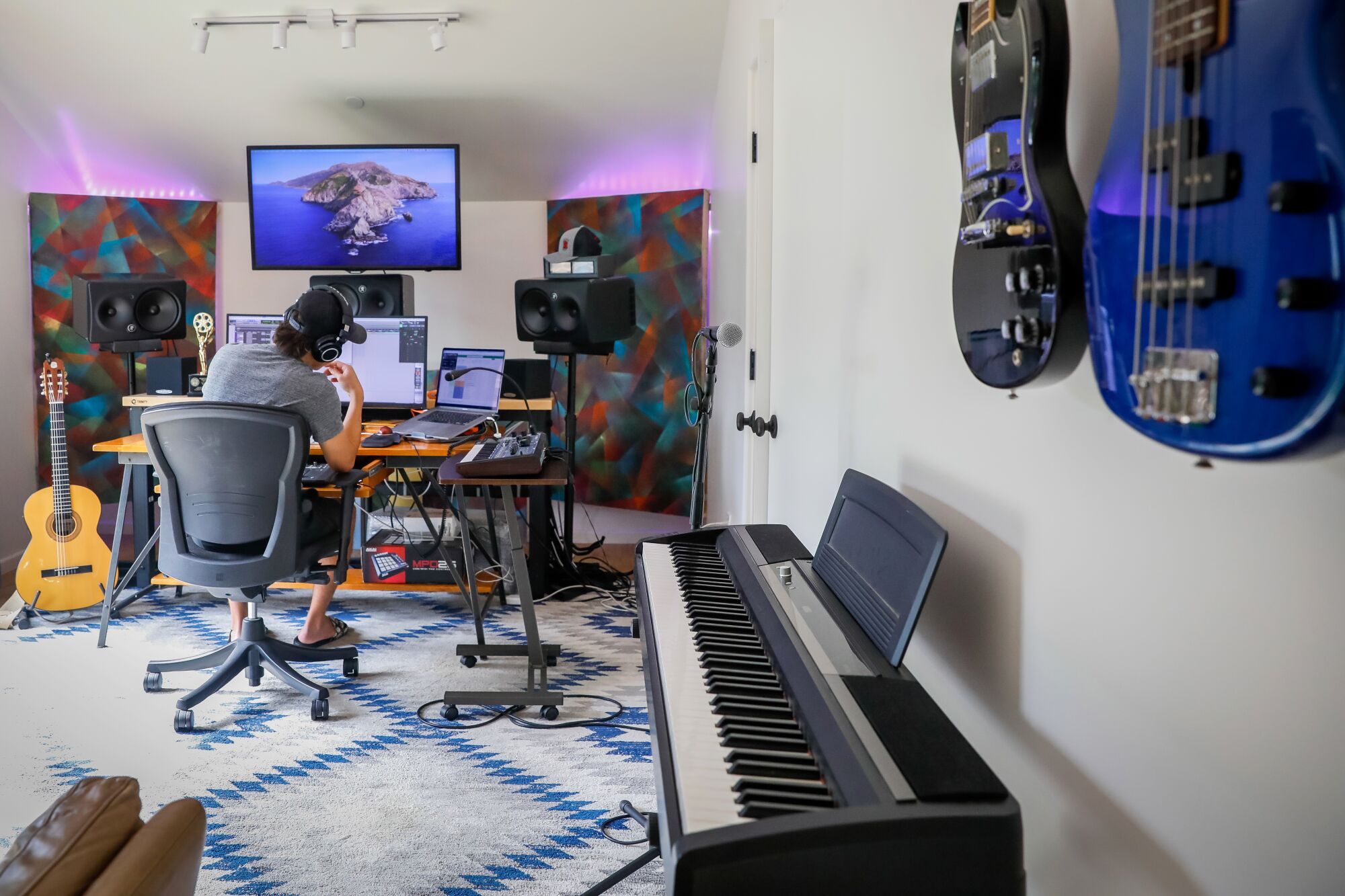 A man sits at a desk full of computers and sound equipment