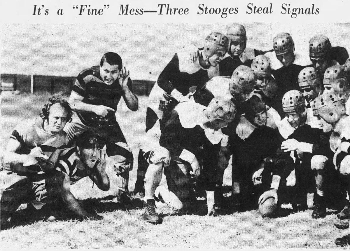 Three men crouch near a huddle of football players.