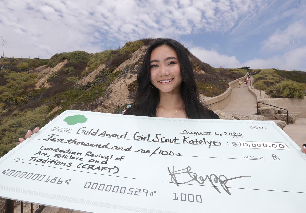 Girl Scout Katelyn Saiki stands with a large representation of her scholarship check from the Girl Scouts of the USA.