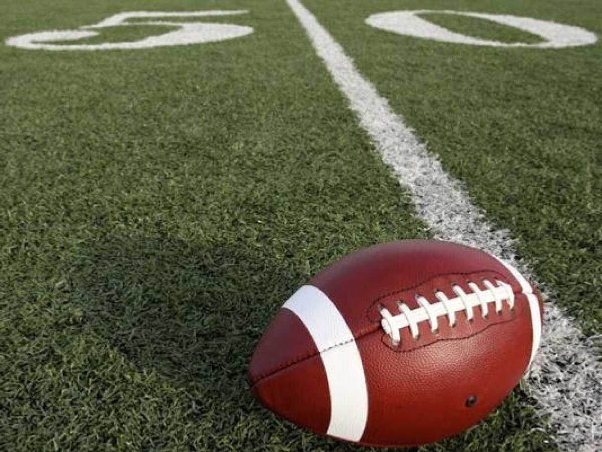 A football on the turf at a field.