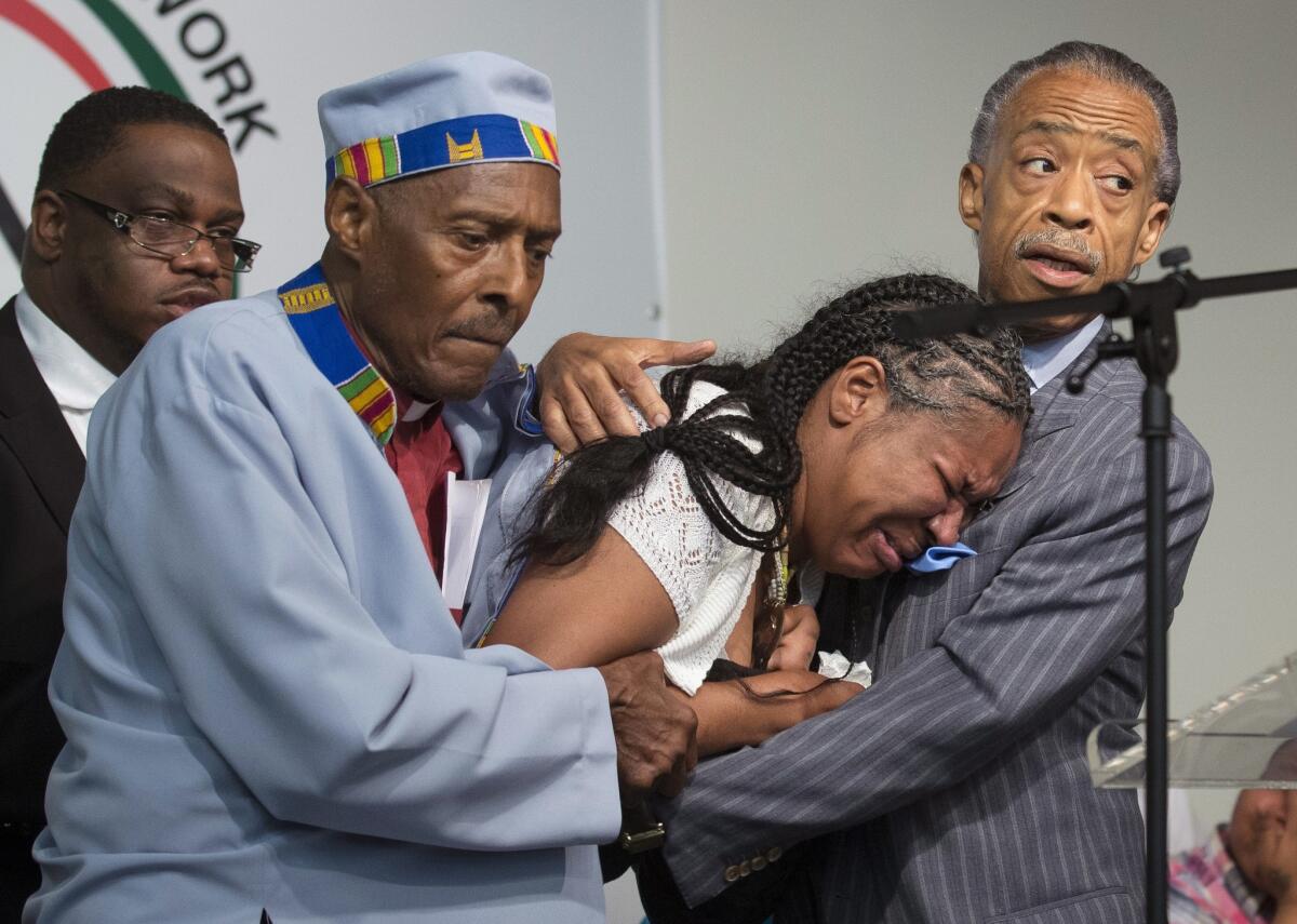 Esaw Garner, wife of Eric Garner, breaks down in the arms of the Revs. Herbert Daughtry, left, and Al Sharpton during a rally over Garner's death in Staten Island, N.Y.