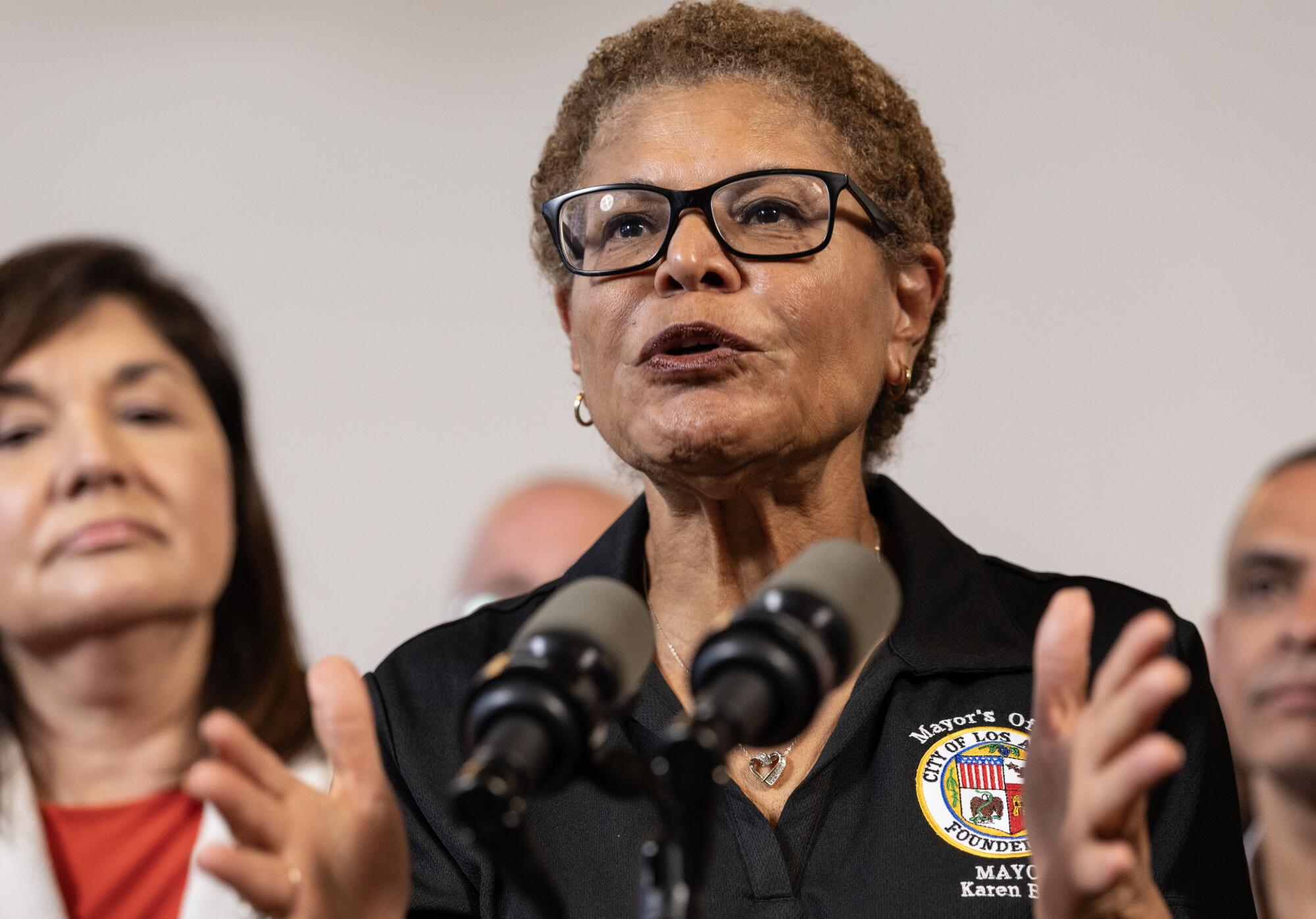 a woman wearing glasses speaks in front of a crowd