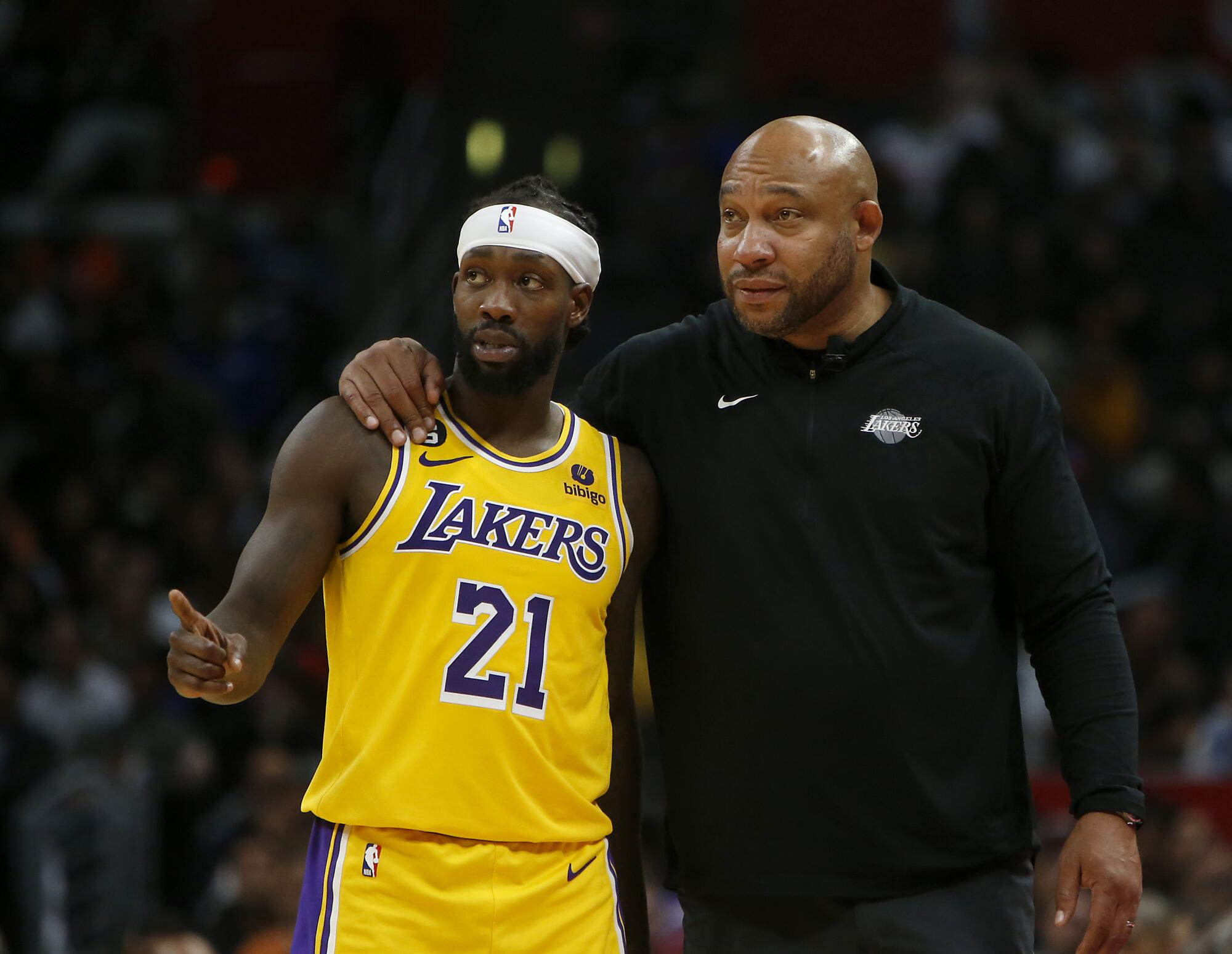 Lakers coach Darvin Ham put his right arm around guard Patrick Beverley as they talk along the sideline