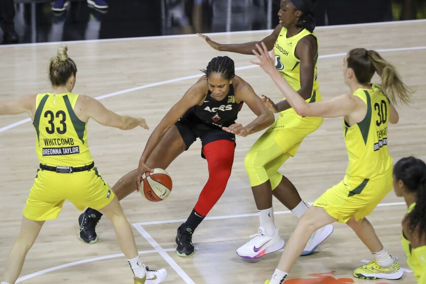Las Vegas Aces' A'ja Wilson, center, drives against the Seattle Storm of, from left, Sami Whitcomb, Natasha Howard, and Breanna Stewart during the first half of a WNBA basketball game Saturday, Aug. 22, 2020, in Bradenton, Fla. (AP Photo/Mike Carlson)