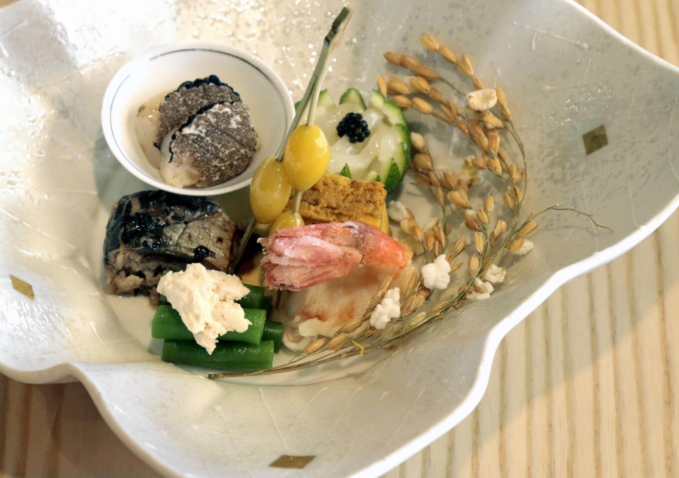 An appetizer assortment includes deep-fried sweet shrimp, sea urchin with egg omelet, deep-fried gingko nuts, sardines simmered in sweet soy sauce, string beans with tofu paste, scallop marinated in truffle oil and squid marinated in a butter spice mixture.