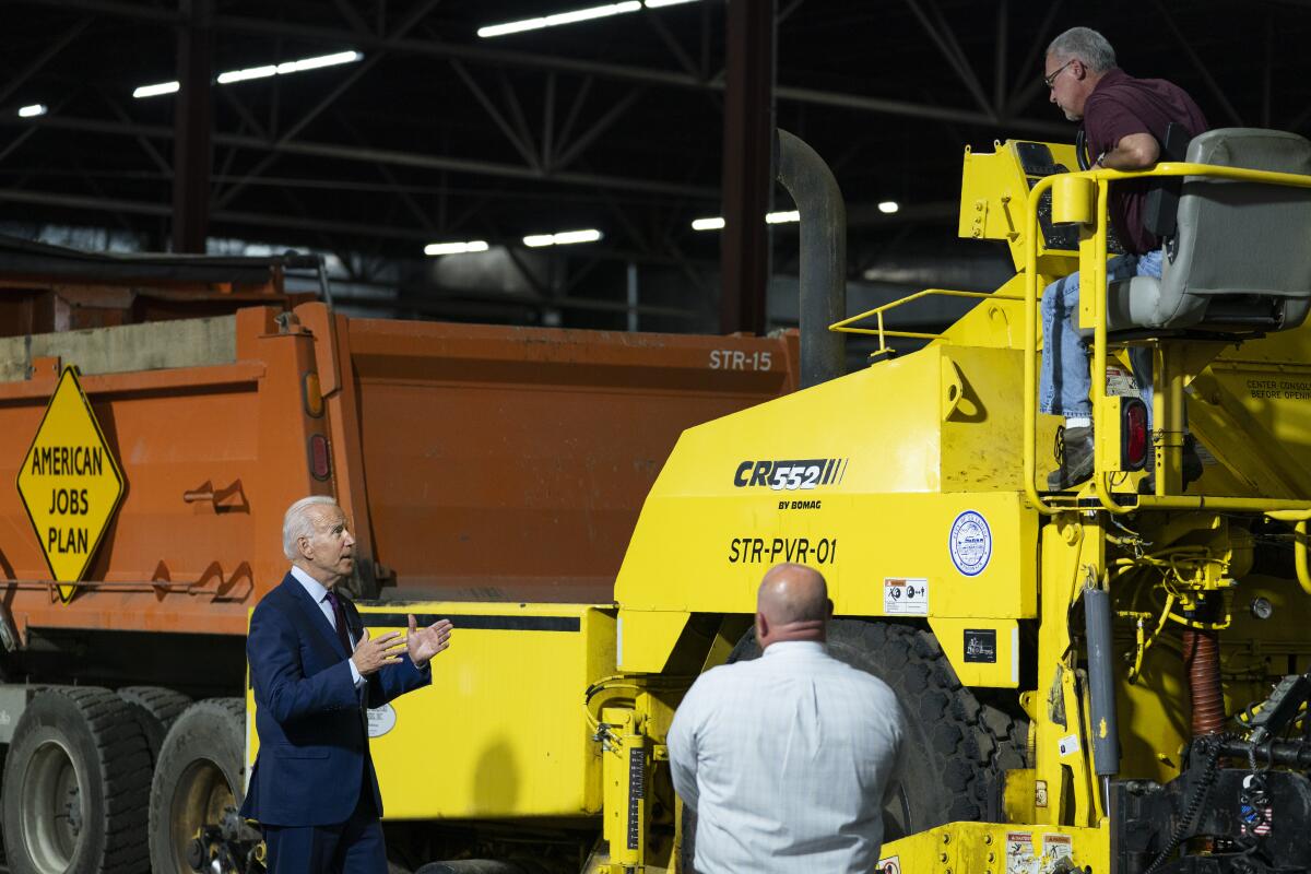 President Biden looks at machinery during a visit to Wisconsin