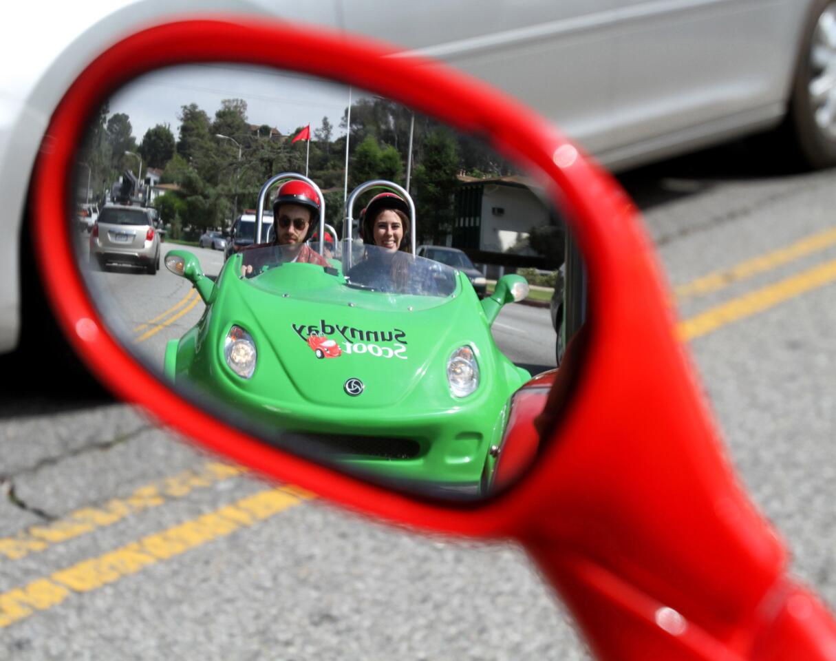 Taylor Kenney, 22 of Los Angeles, drives a three-wheel scooter with friend Cameron Sarradet toward the old Los Angeles Zoo during a three-hour, Red Carpet tour offered by Burbank-based Sunnyday Scoot on Friday, June 5, 2015.