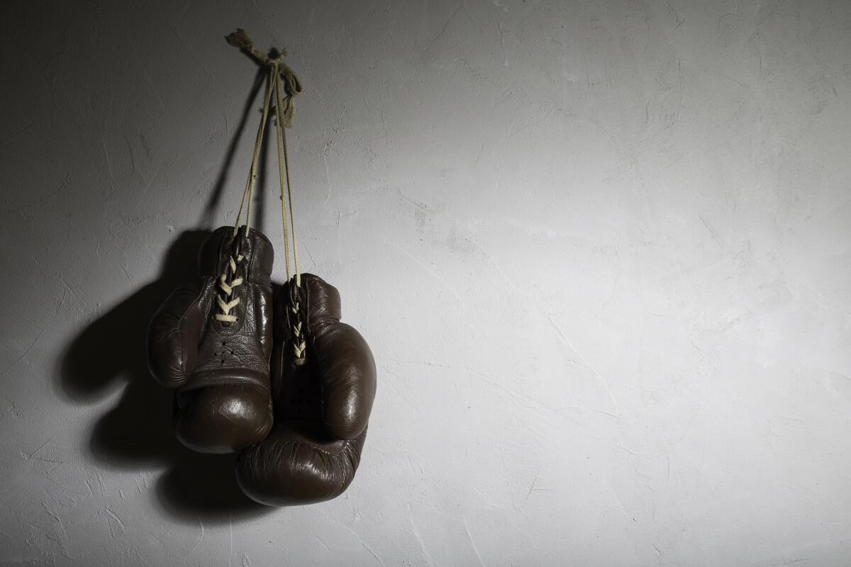A pair of boxing gloves hanging from a cement wall.