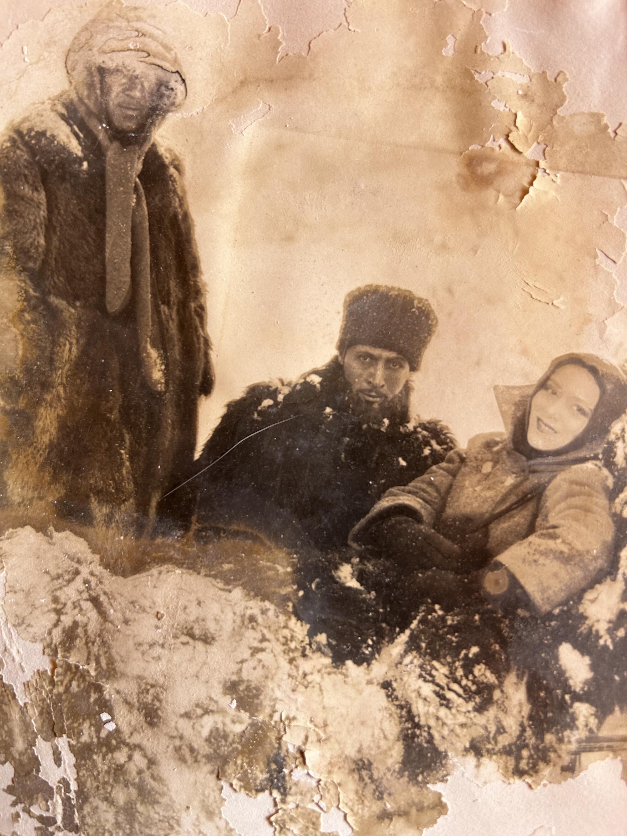 Three people in a vintage sepia-toned photo in wintery costumes.