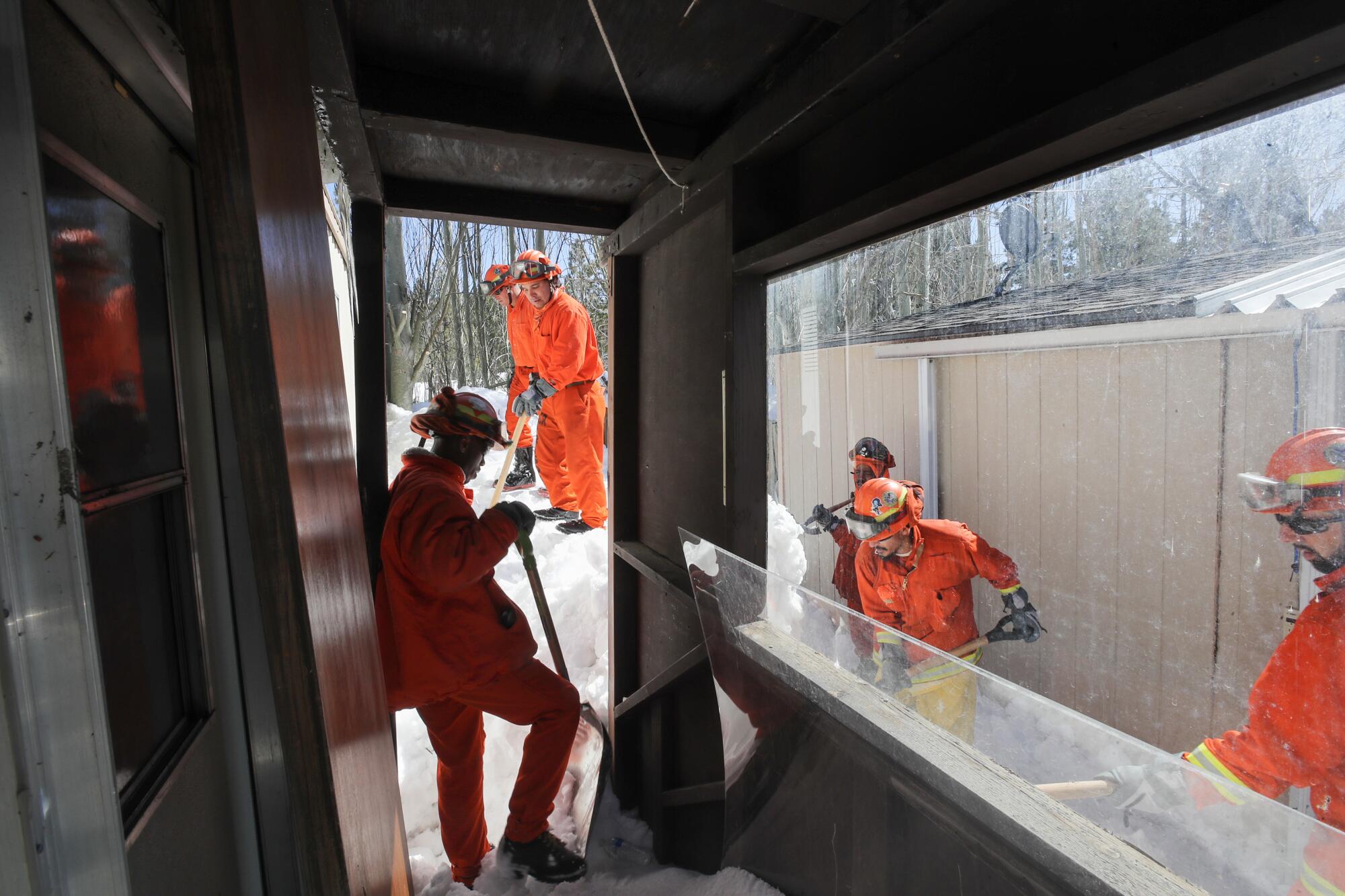 Cal Fire Fenner Canyon fire crew inmates dig snow from around a residence at a Big Bear Lake trailer park on Friday.