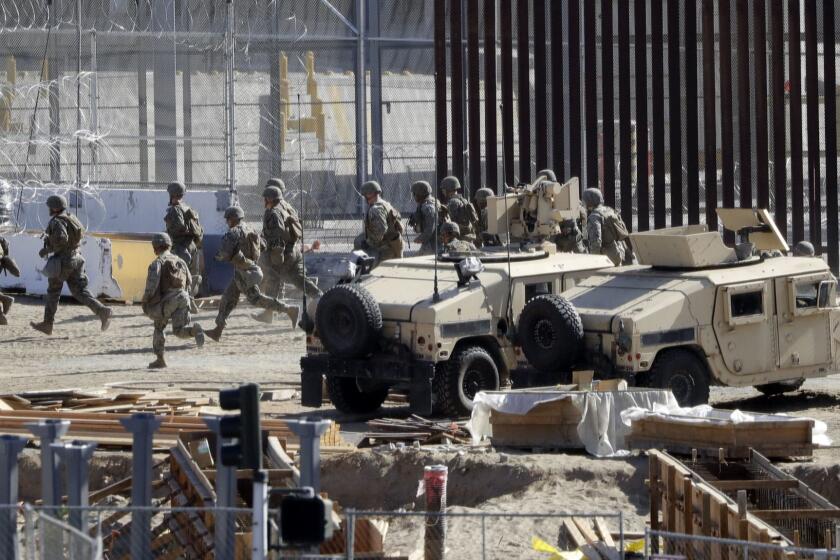 Officials run in a staging area in the San Ysidro port of entry Sunday, Nov. 25, 2018, in San Diego. Migrants approaching the U.S. border from Mexico were enveloped with tear gas Sunday after a few tried to breach the fence separating the two countries. (AP Photo/Gregory Bull)