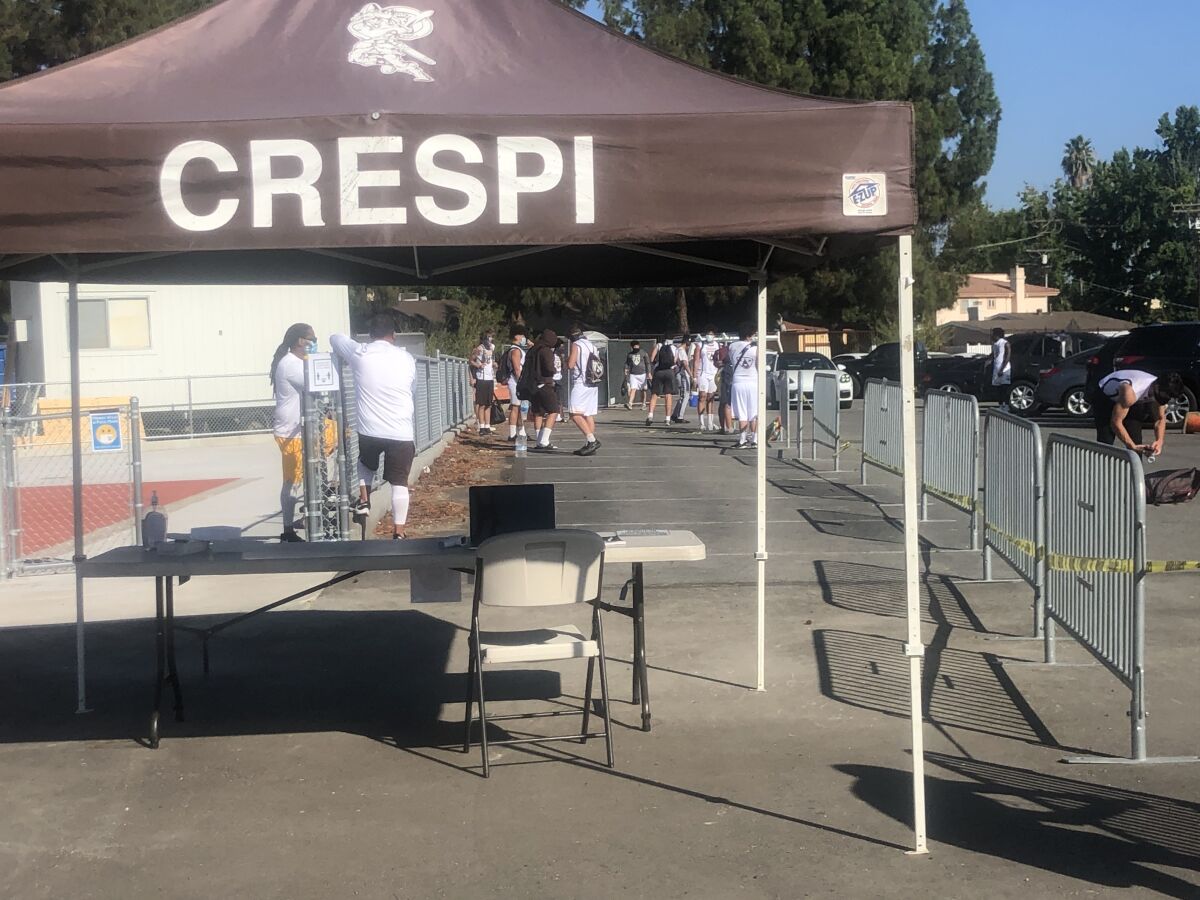Players wait to check in for a temperature check at Crespi High in Encino.