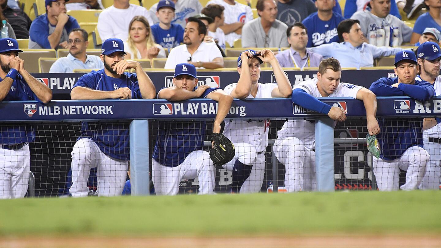 Dodger players watch from the dugout trailing 8-1 in Game 5 of the NLCS at Dodger Stadium