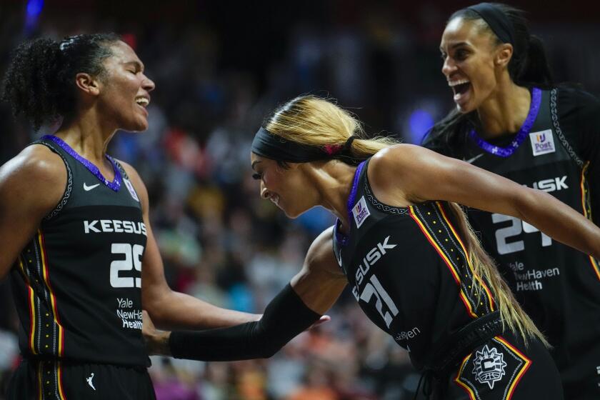 Alyssa Thomas #25, DiJonai Carrington #21 and DeWanna Bonner #24 of the Connecticut Sun smile and interact during a game