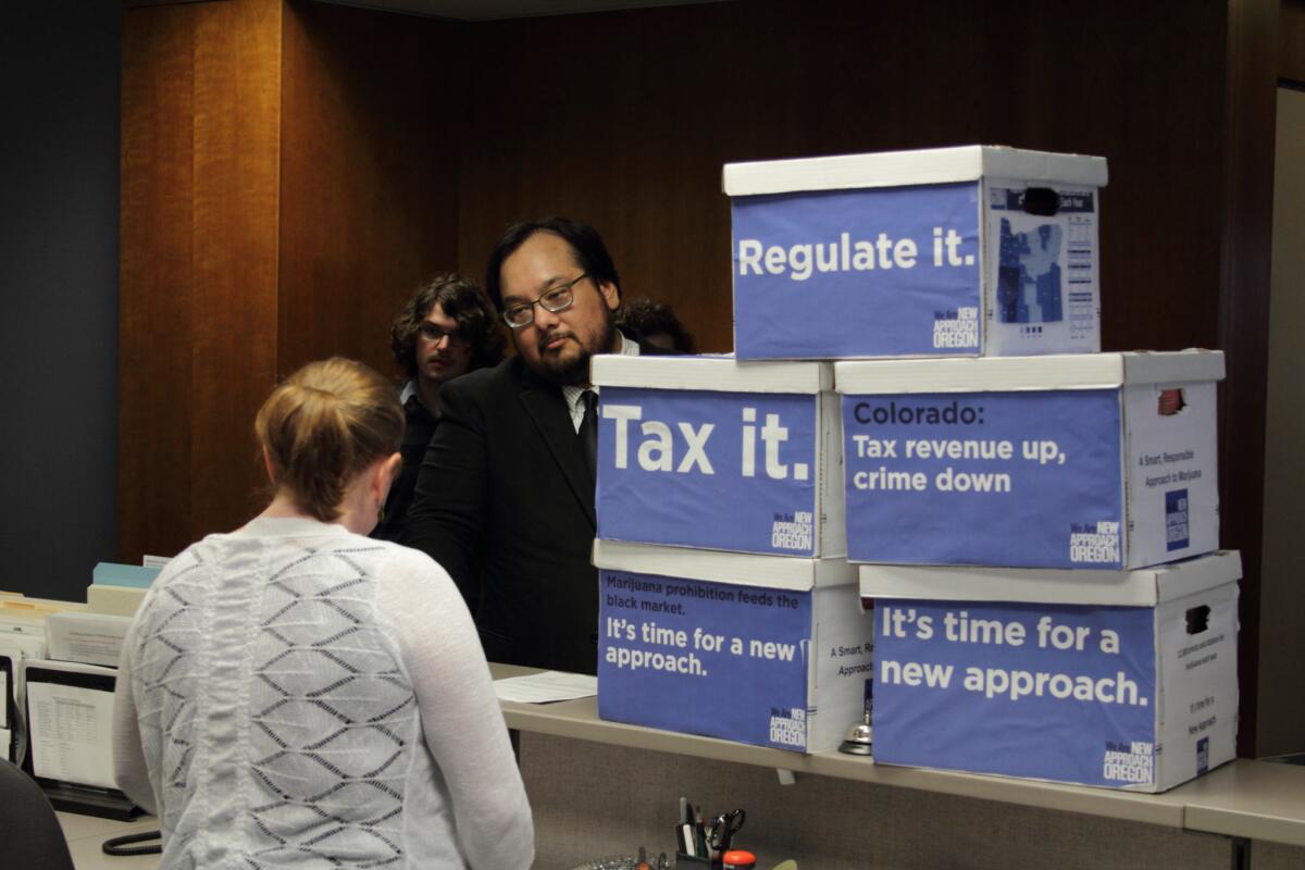 Anthony Johnson, director of New Approach Oregon, delivers boxes of signed petitions to an election worker on June 26 in Salem, Ore. New Approach's ballot initiative to legalize marijuana submitted enough signatures to qualify for the November ballot.