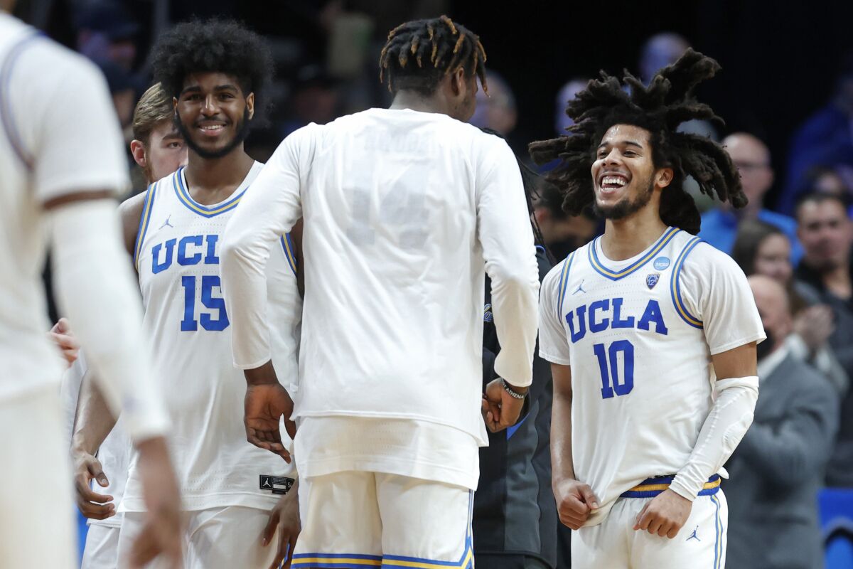 UCLA guard Tyger Campbell reacts with center Myles Johnson and Kenneth Nwuba.
