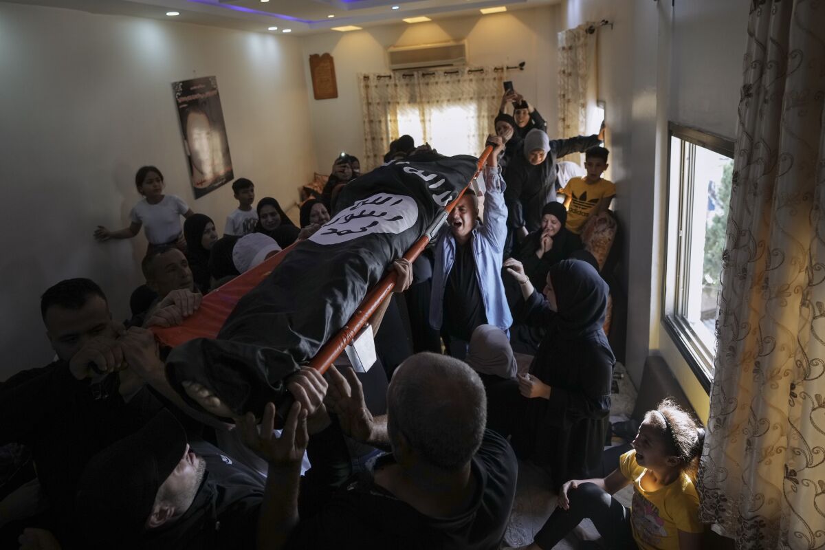 Mourners carry the body of Palestinian Bara Lahlouh, 24, at his family home, in the West Bank town of Jenin, Friday, June 17, 2022. Israeli forces shot dead Lahlouh and another two Palestinians and wounded eight others early Friday during a military operation in the occupied West Bank town of Jenin, the Palestinian Health Ministry said. The military said the troops traded fire with militants. (AP Photo/Nasser Nasser)