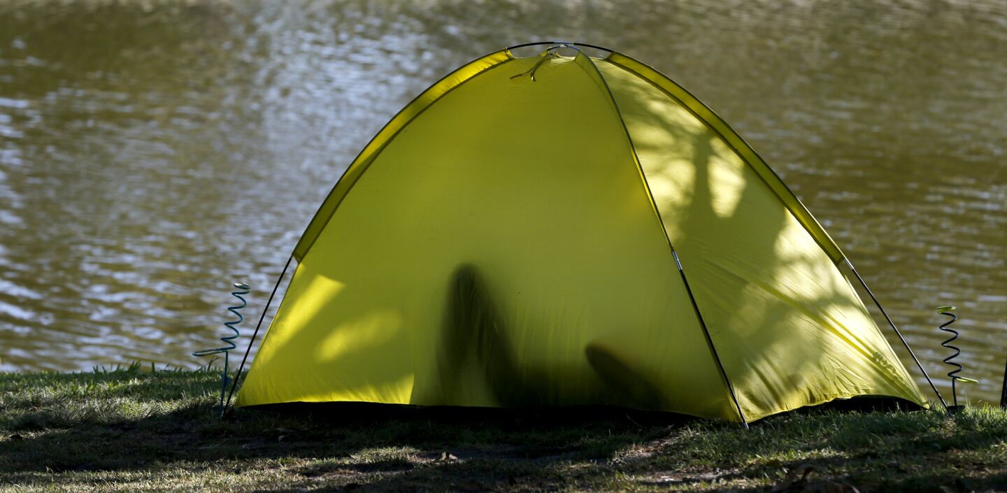 A person is silhouetted while relaxing in a tent by the water at Whittier Narrows Recreation Area in South El Monte.