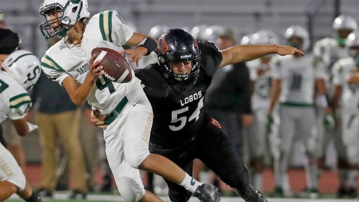 Los Amigos' Sergio Rodas, right, puts pressure on Saddleback quarterback Alex Soto in a nonleague game at Garden Grove High on Sept. 6. Harold McDowell served as the Lobos' defensive coordinator for the past five seasons.