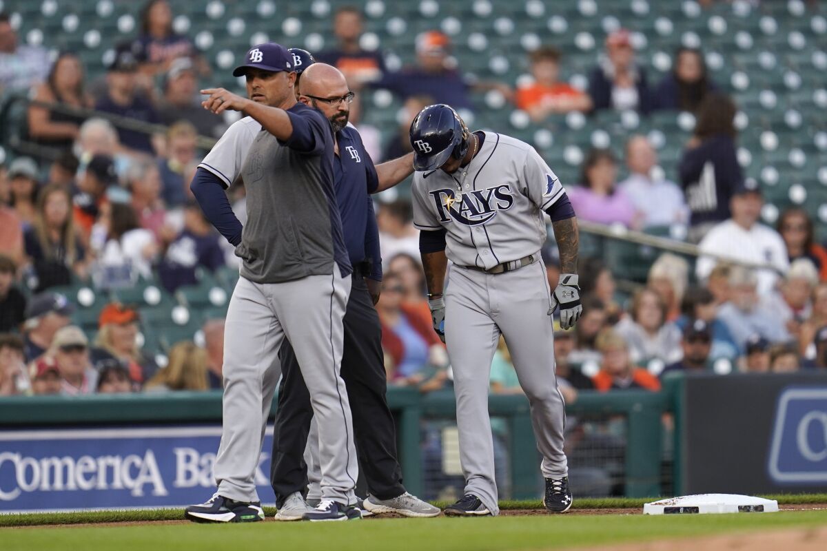 Tampa Bay Rays manager Kevin Cash, from left, signals for a pinch runner as team trainer Joe Benge helps Wander Franco to the dugout from third base against the Detroit Tigers in the first inning of a baseball game in Detroit, Friday, Sept. 10, 2021. (AP Photo/Paul Sancya)