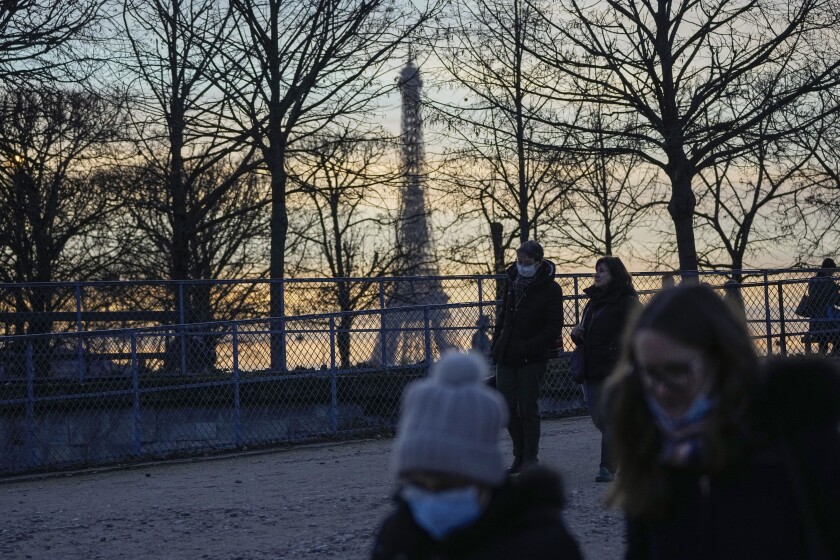 People wearing face masks to protect against COVID-19 walk at Tuilerie garden in Paris, Thursday, Dec. 9, 2021. The World Health Organization says early evidence suggests the omicron variant may be spreading faster than the highly transmissible delta variant but brings with it less severe coronavirus disease. Eiffel Tower in the background. (AP Photo/Michel Euler)