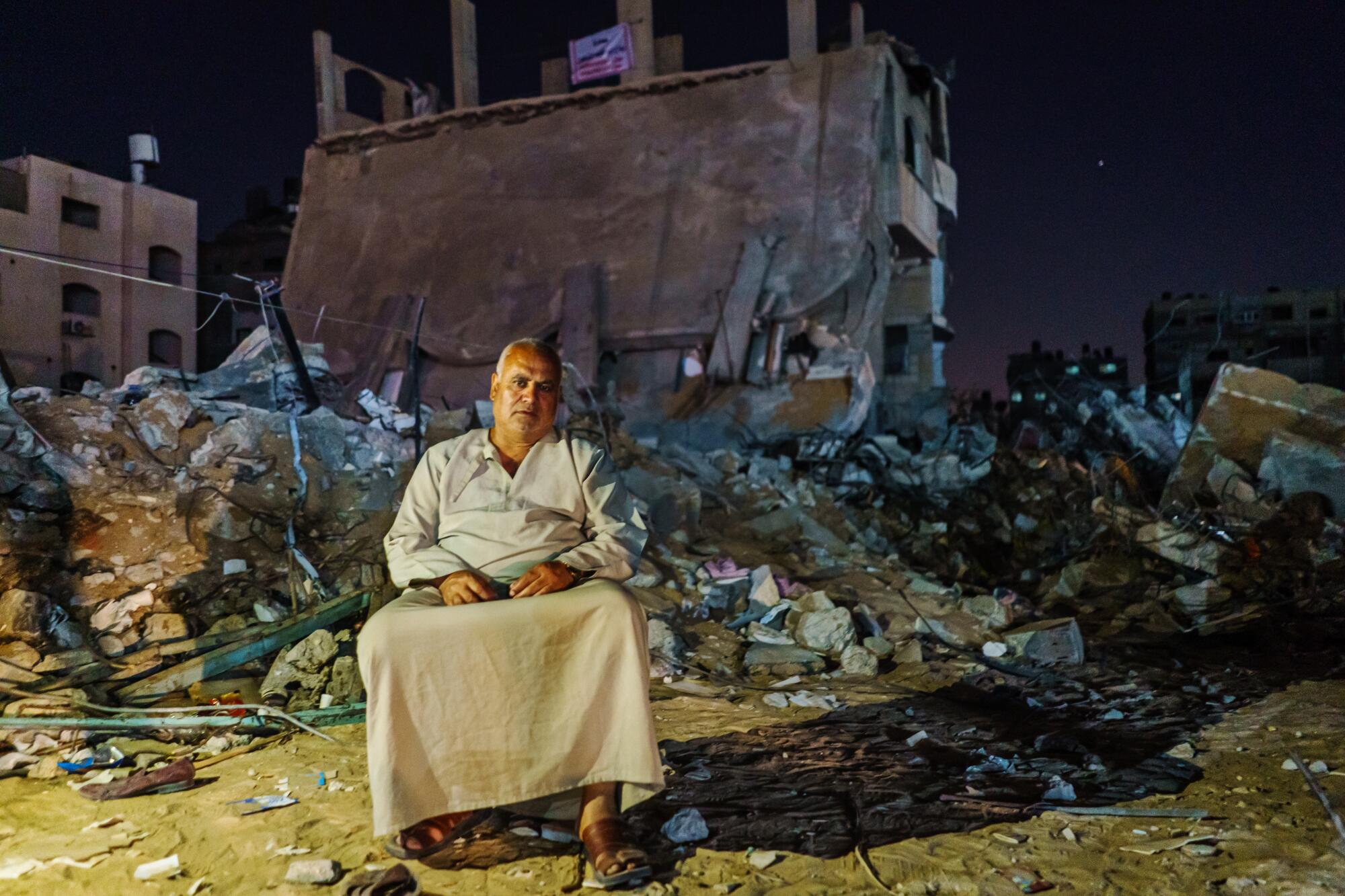 Rabah Al-Madhoun sits in front of the remains of his building in Gaza City.