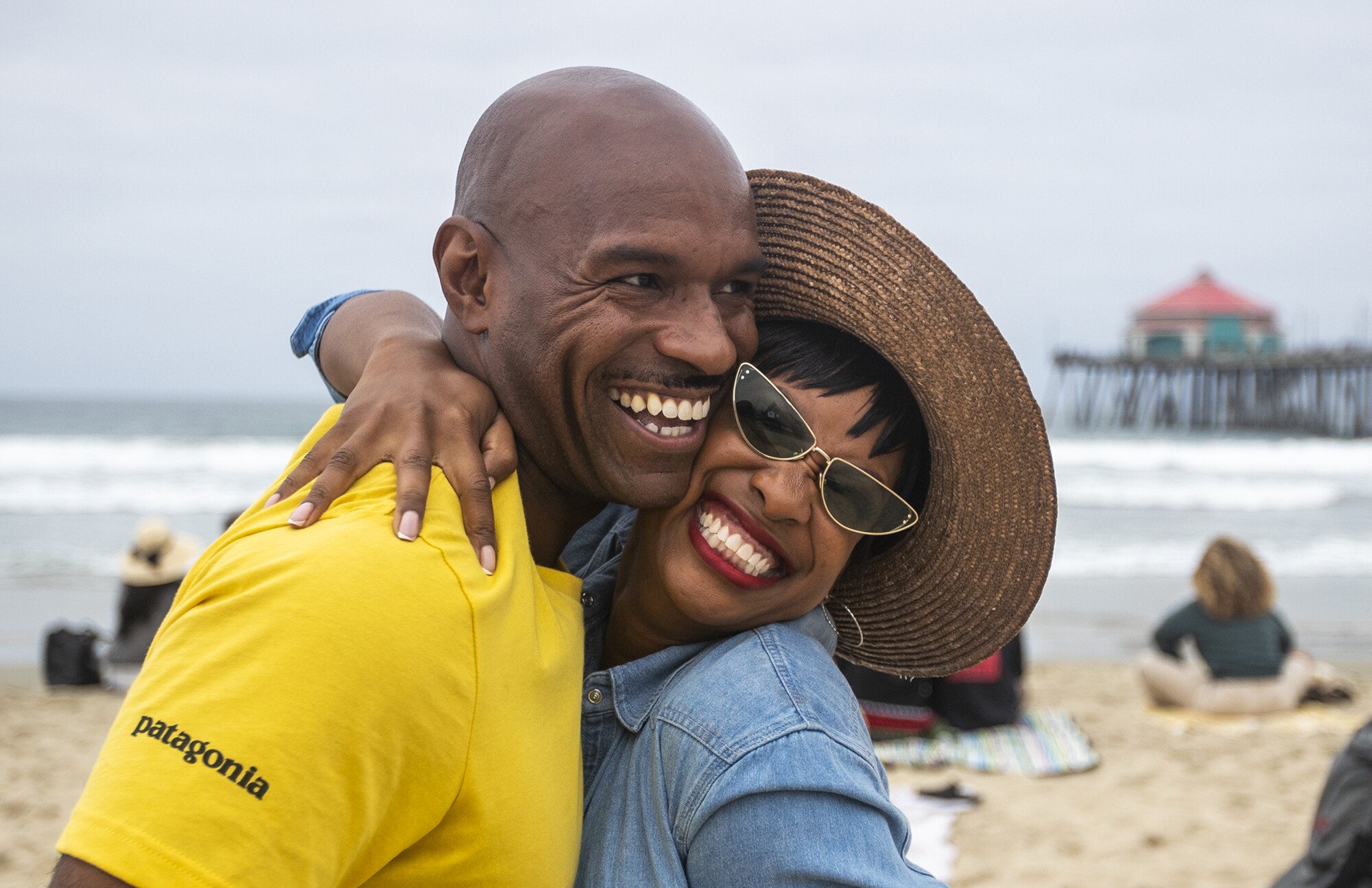 A woman in sunglasses hugs a smiling man.