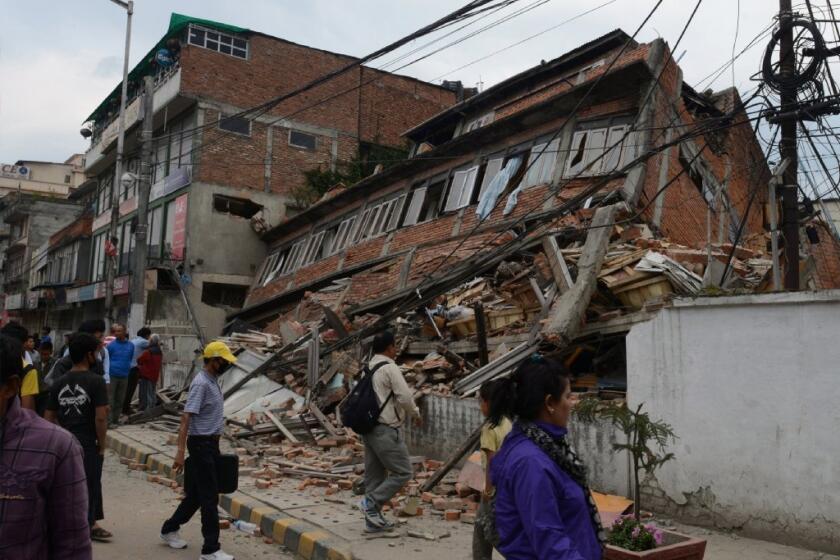 People walk past a collapsed bulding in Katmandu, Nepal, after a deadly earthquake on April 25.