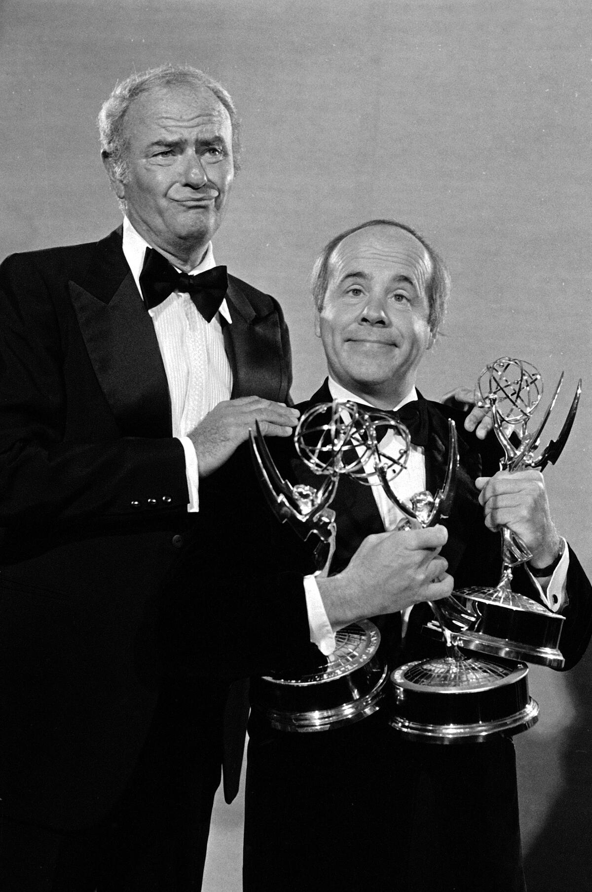 Harvey Korman and Tim Conway make funny faces while holding three Emmy Awards 