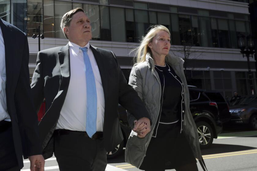 In this file photo, investor John Wilson arrives at federal court in Boston with his wife Leslie.