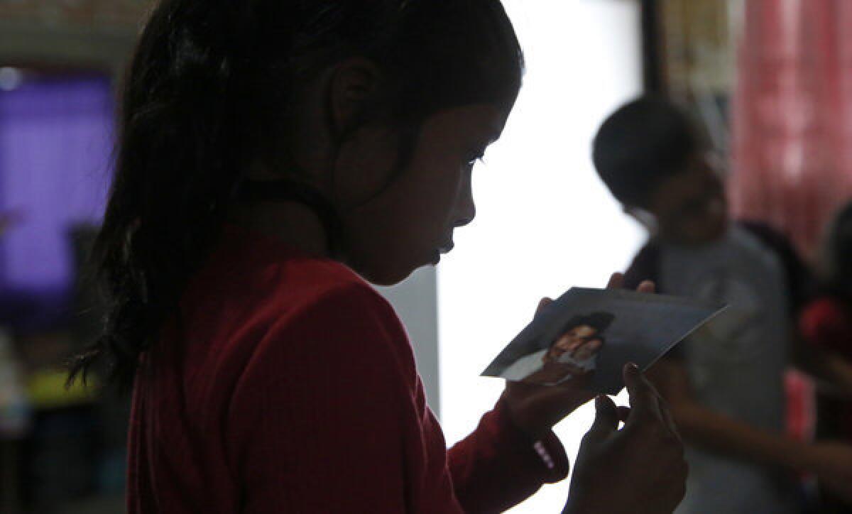 Maria Ireta stares at a snapshot of her father Benigno and herself when she was a baby in San Diego. With the family separated by the border for the last three years, old photos and phone calls are important emotional links for the children.