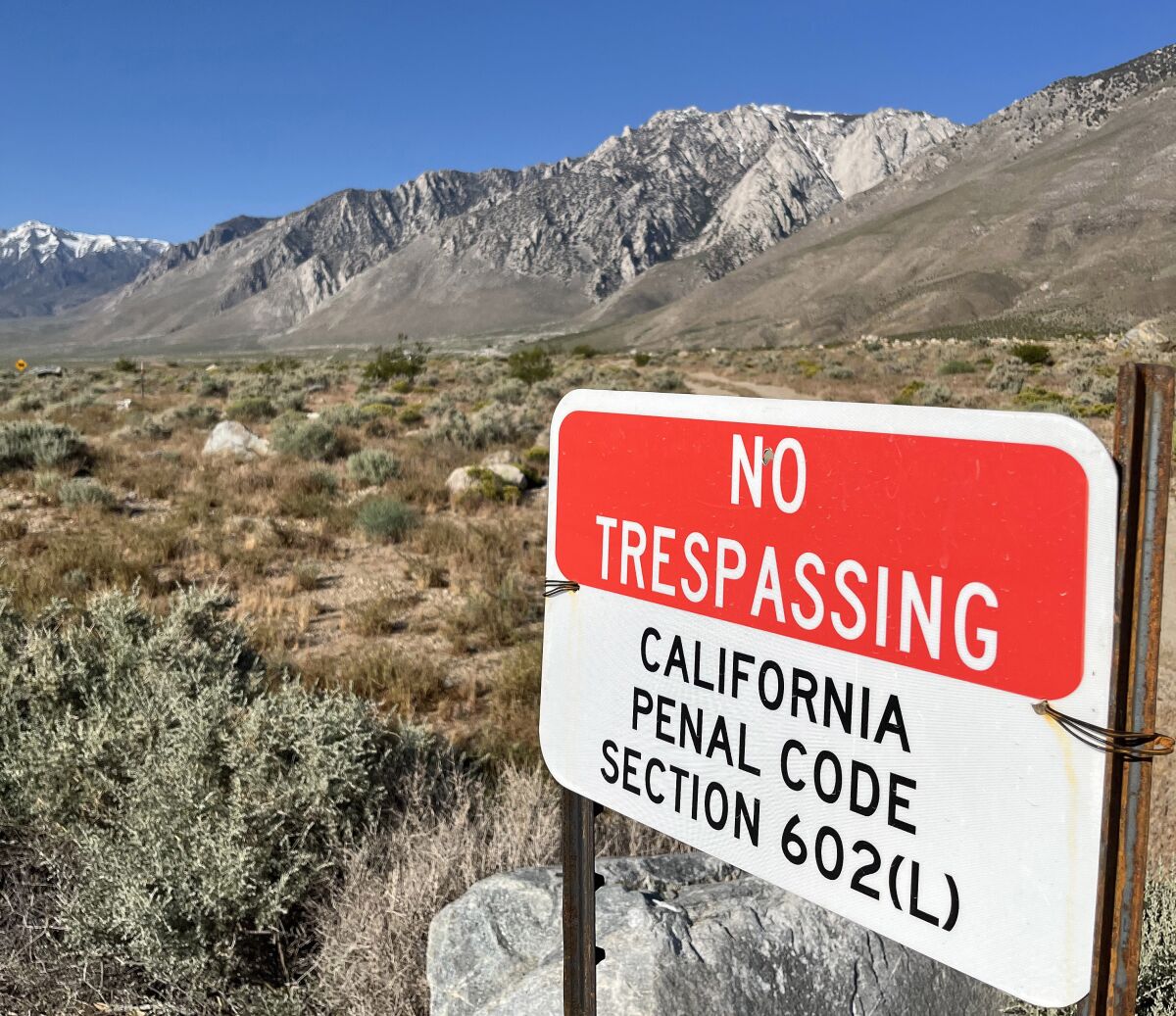 A "no trespassing" sign with mountains in the background.
