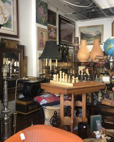 A chess set on a table amid other furnishings and paintings at Casa Victoria thrift store in Echo Park.