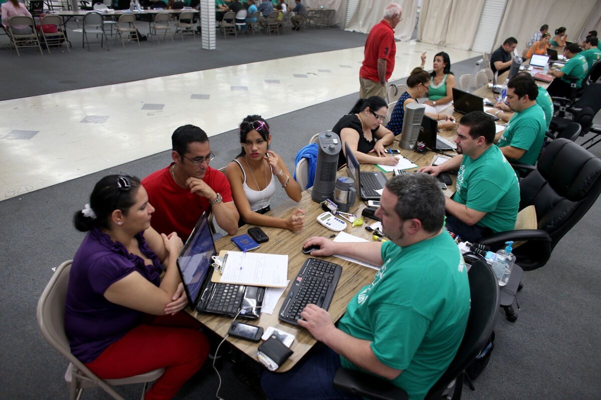 People work with advisors in Miami to purchase health insurance under the Affordable Care Act at a store setup in the Mall of Americas.
