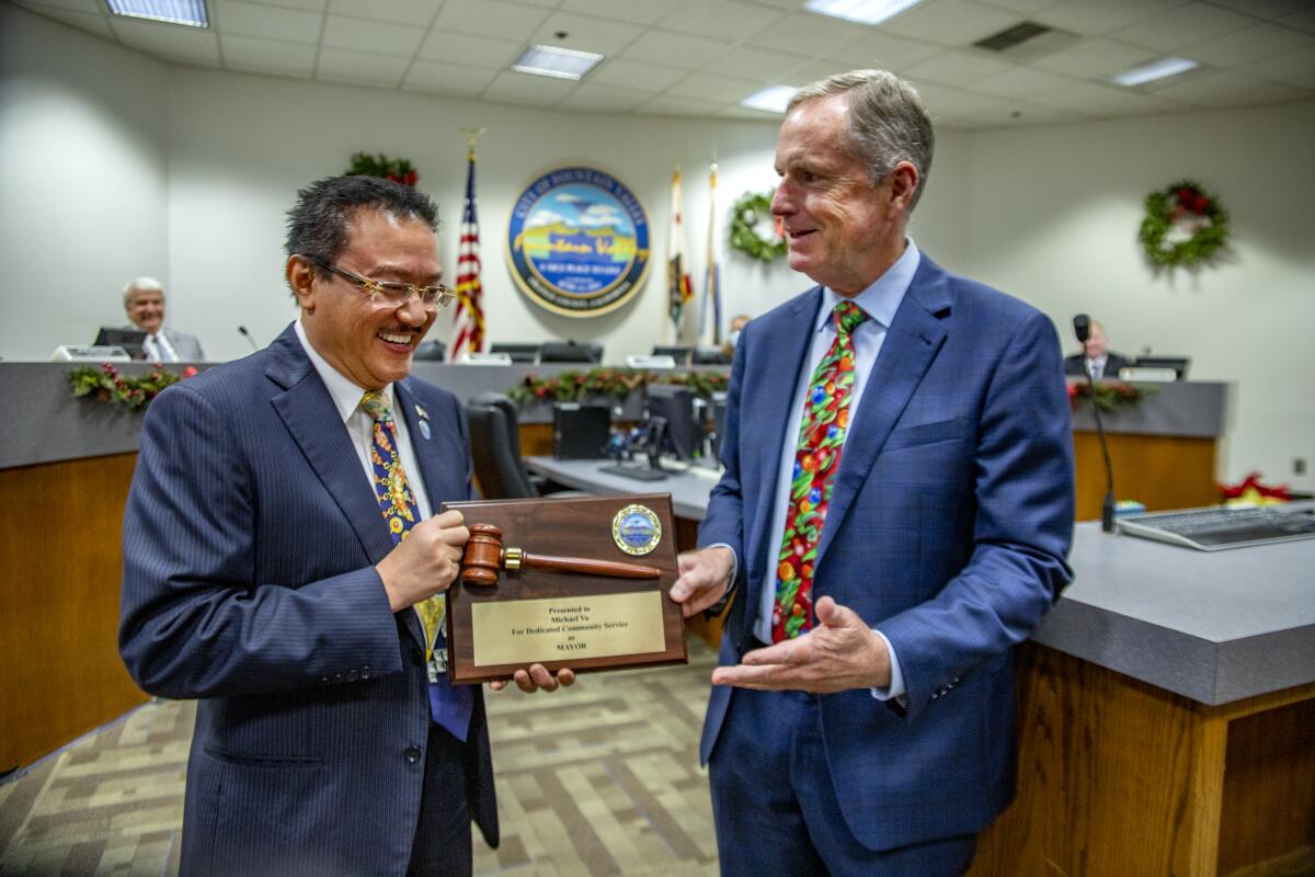 Incoming Mayor Patrick Harper receives a ceremonial gavel from Michael Vo during a transition meeting in December.