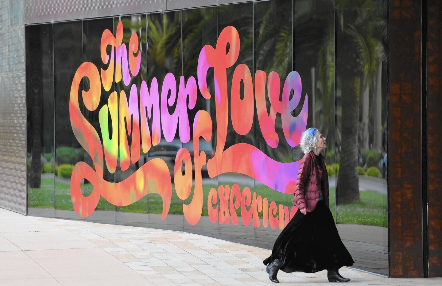 A woman walks toward the entrance to the de Young Museum, which recently debuted an exhibit revolving around 1967's Summer of Love.