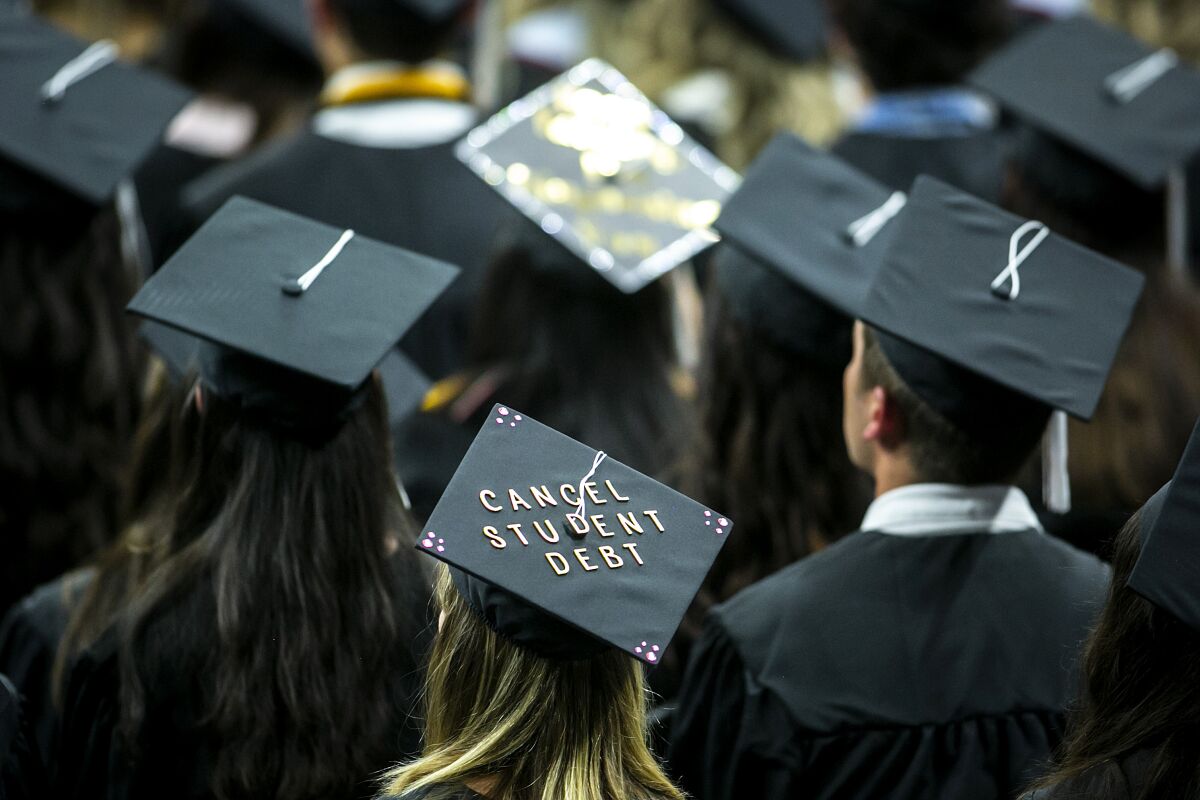 The words "Cancel student debt" appear on a cap of a university graduate candidate
