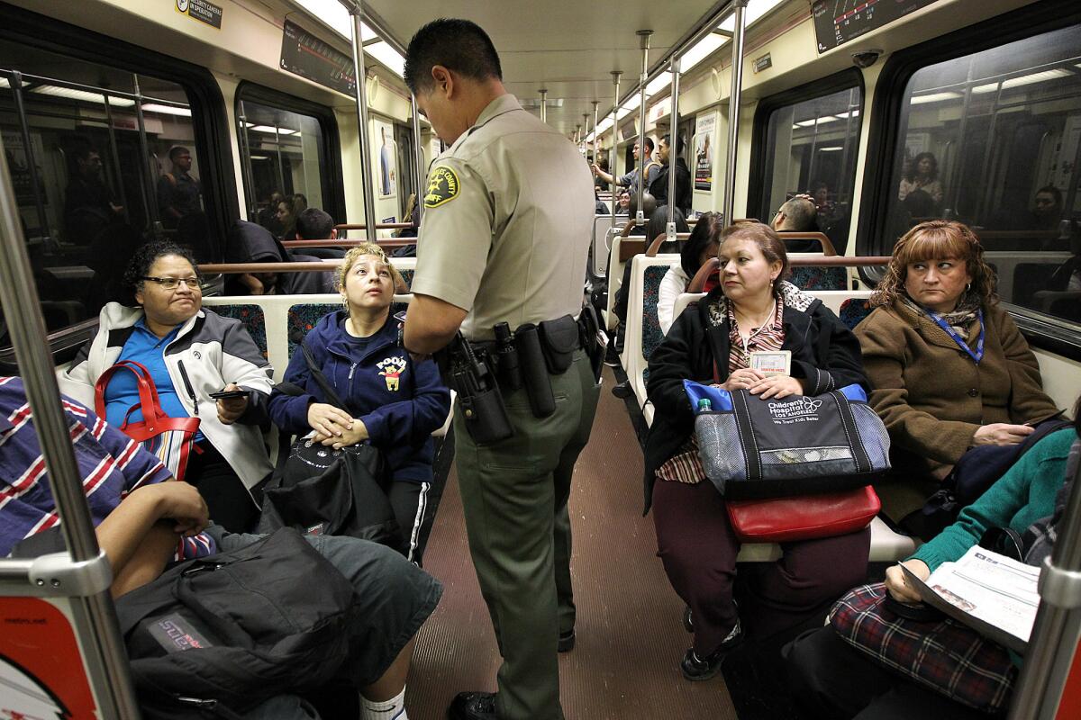 A Los Angeles County Sheriff's Department deputy performs a fare check during a patrol through a Metro train in downtown Los Angeles.