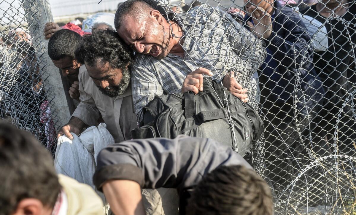Syrians fleeing the war pass through border fences to enter Turkish territory illegally, near the Turkish border crossing at Akcakale.