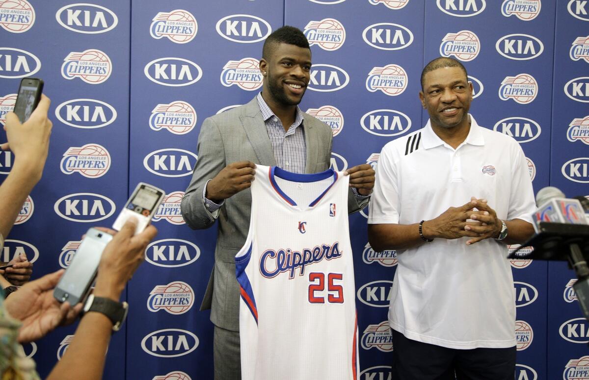 Clippers first-round draft choice Reggie Bullock, left, holds his jersey while posing for photographs with Coach Doc Rivers during a news conference Monday.