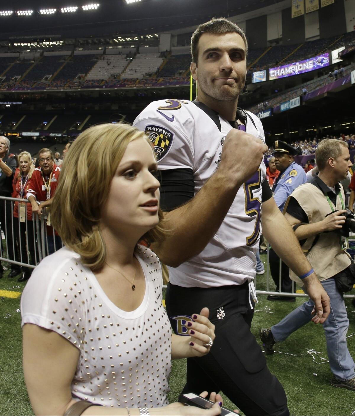 Baltimore quarterback Joe Flacco and his wife, Dana, walk off the field after the Super Bowl in New Orleans.