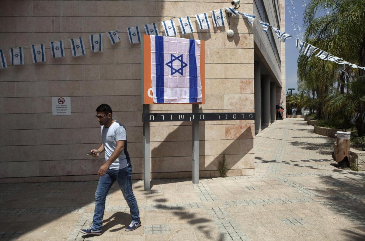 An Israeli man walks past the Orange company logo covered with an Israeli flag at Partner Communications' offices in Rosh Haayin, Israel, on June 4.