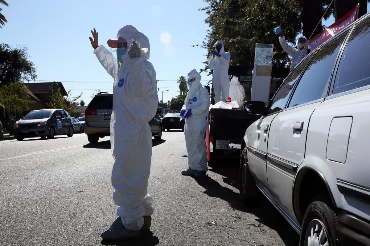 Protesters in white protective suits wave to passing drivers