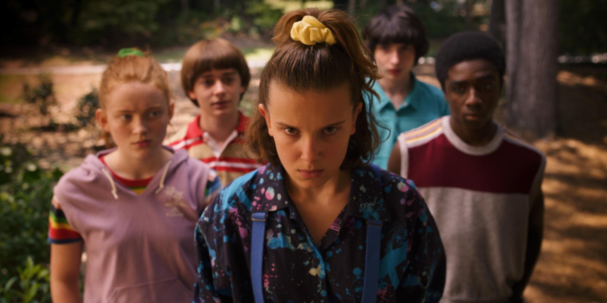 Five children wearing colorful clothes and staring forward