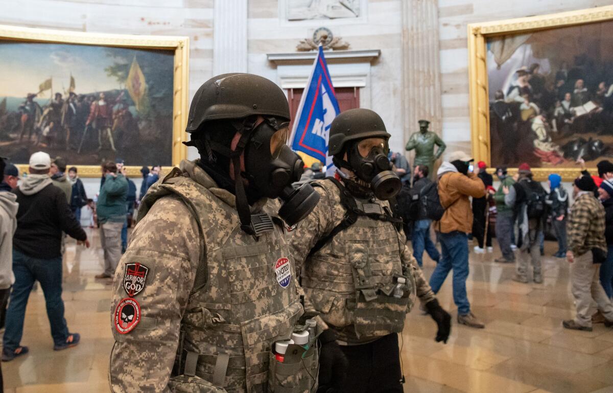 Supporters of US President Donald Trump wear gas masks and military-style apparel as they walk around inside the Rotunda.