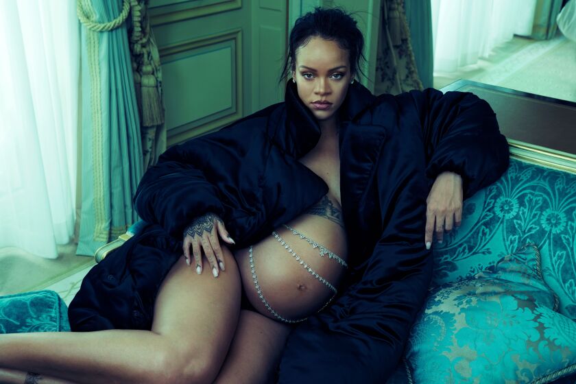 A pregnant woman lying on sofa while wearing a coat and diamond belly chains