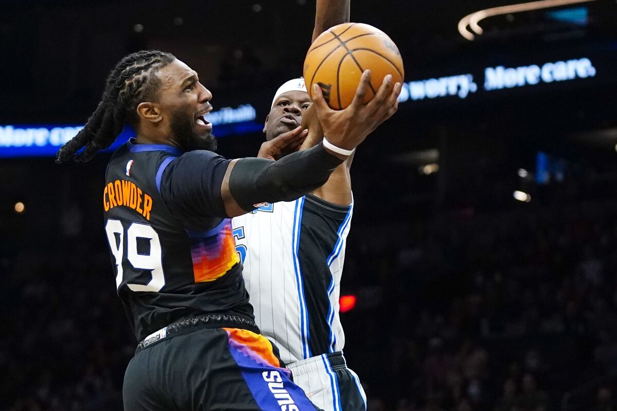 Phoenix Suns forward Jae Crowder, left, drives past Orlando Magic center Mo Bamba to score during the first half of an NBA basketball game Saturday, Feb. 12, 2022, in Phoenix. (AP Photo/Ross D. Franklin)