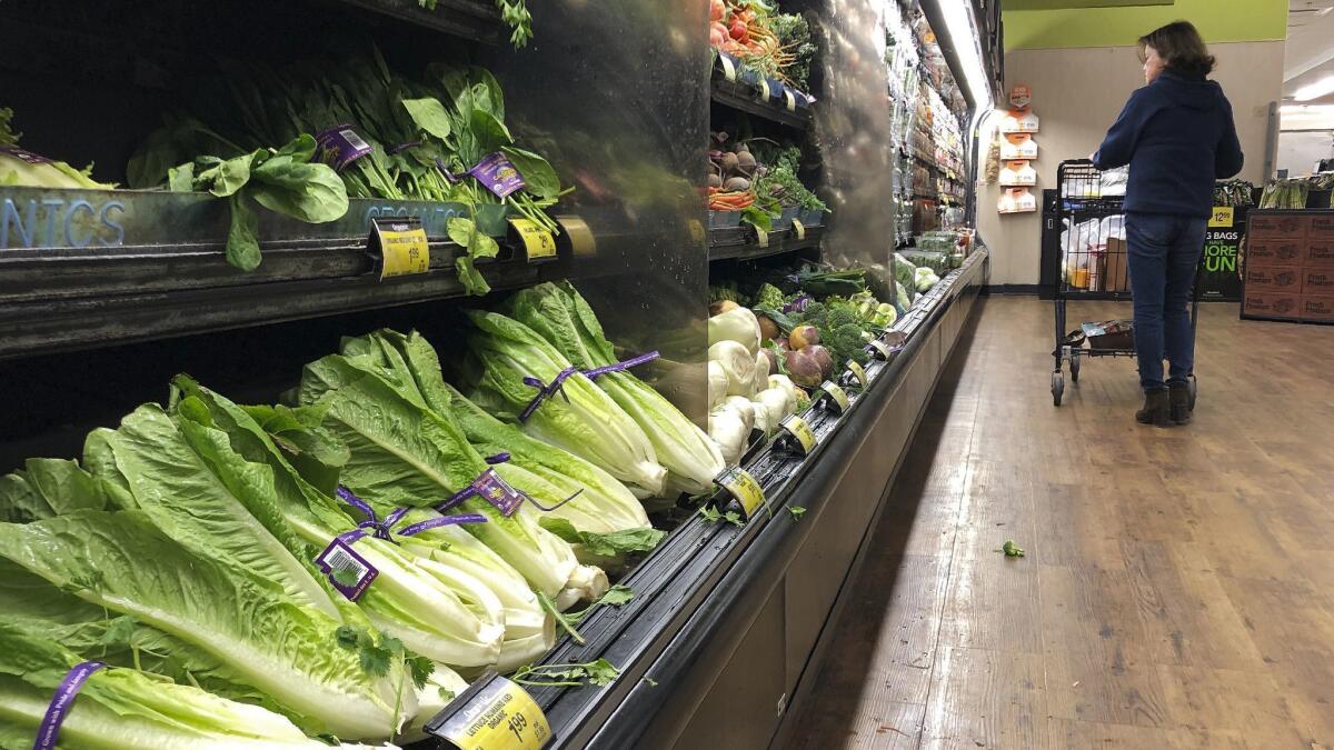 Romaine Lettuce still sits on the shelves as a shopper walks through the produce area of an Alberstons market Tuesday, Nov. 20, 2018, in Simi Valley, Calif. Health officials in the U.S. and Canada told people Tuesday to stop eating romaine lettuce because of a new E. coli outbreak. (AP Photo/Mark J. Terrill)
