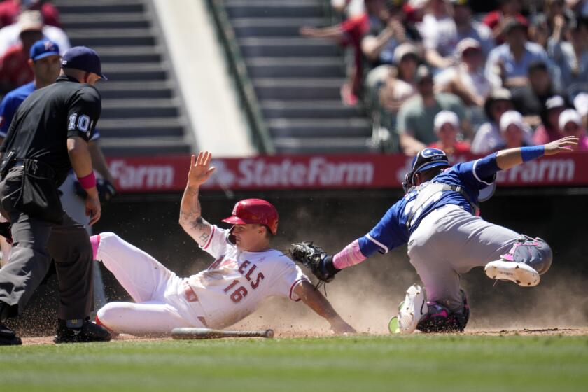Los Angeles Angels' Mickey Moniak, center, scores on a double by Willie Calhoun as Kansas City Royals catcher Freddy Fermin, right, makes a late tag while home plate umpire Phil Cuzzi watches during the sixth inning of a baseball game Sunday, May 12, 2024, in Anaheim, Calif. (AP Photo/Ashley Landis)
